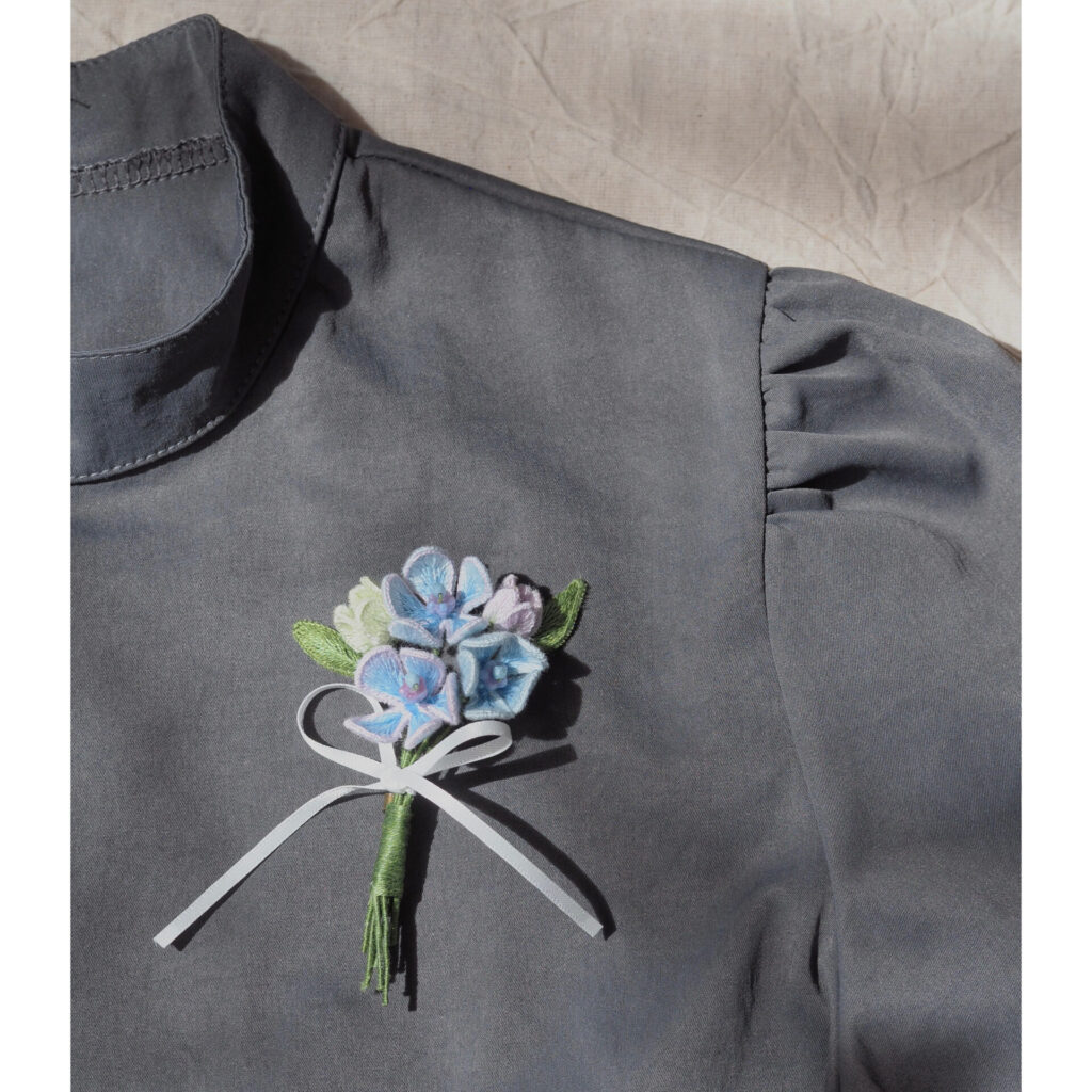 ブルースターブーケブローチの着用イメージ。